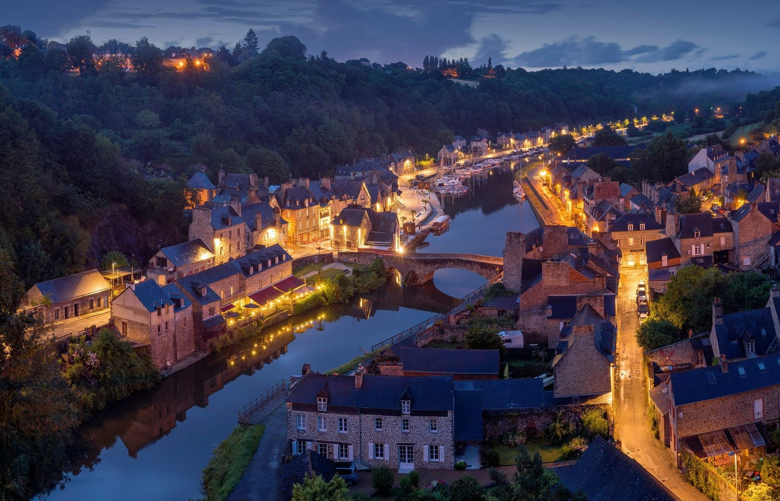 Twilight view of a riverside village with a stone bridge and canal