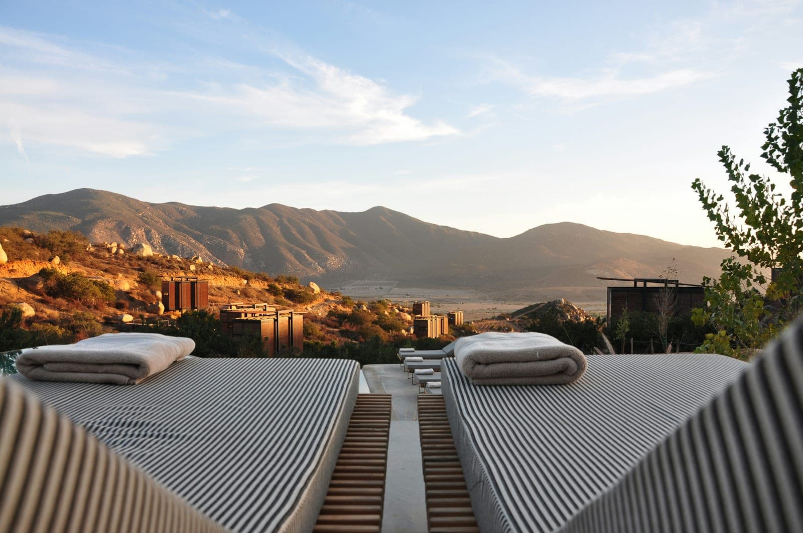 Sun loungers on a terrace overlooking a mountain valley at sunset