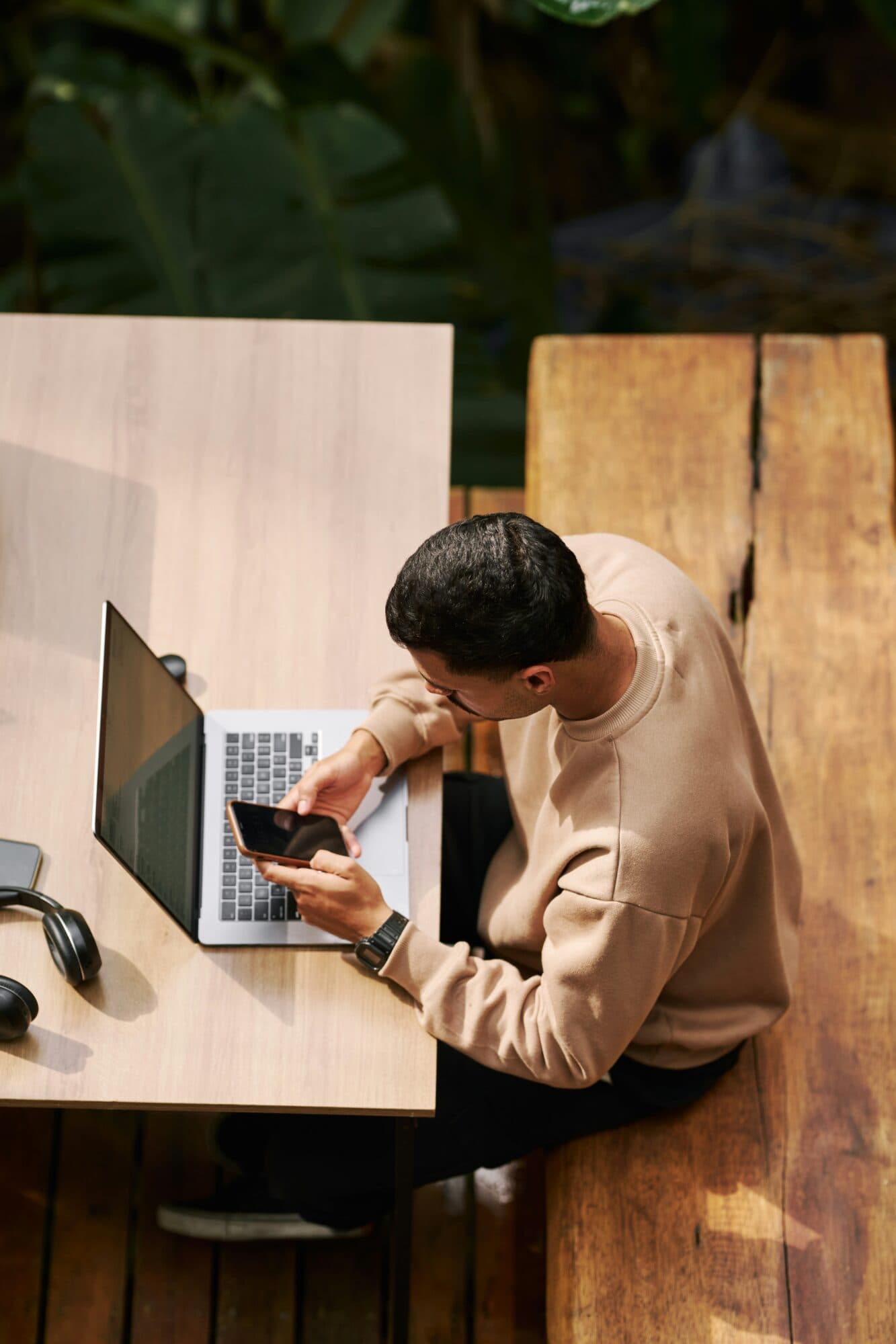 Traveler using a laptop and phone at a wooden table