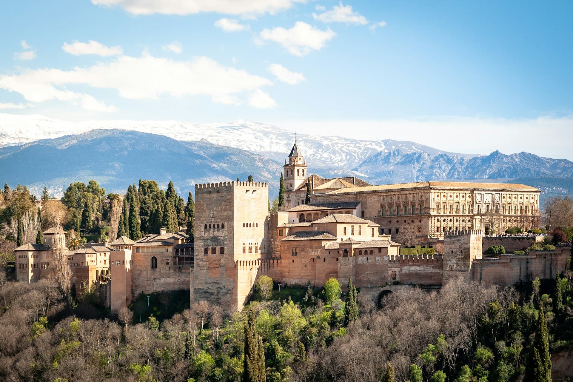 Aerial view of the Alhambra palace in Granada with snow-capped mountains in the distance