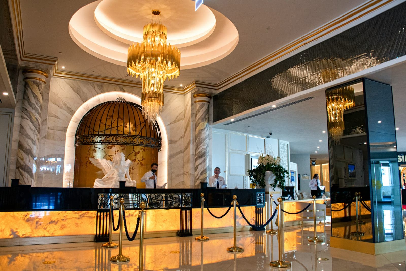 Grand hotel lobby with gold chandeliers and a front desk